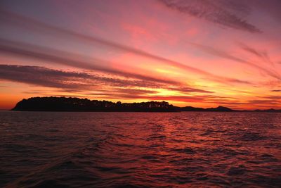 Scenic view of sea against dramatic sky during sunset