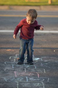 Full length of boy playing hopscotch on road