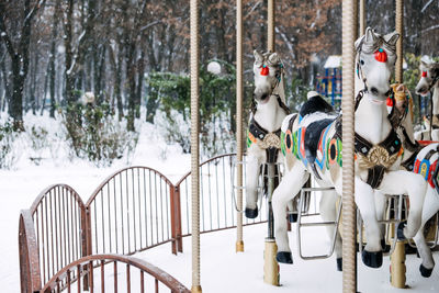 Merry-round-go horse carousel in winter park. winter snow landscape with retro carousel roundabout