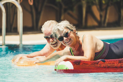 Portrait of smiling senior couple swimming in pool