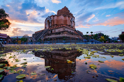 Reflection of building on water against cloudy sky