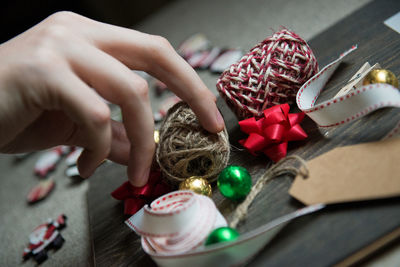 Cropped hand holding christmas decorations on table