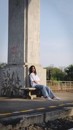 Full length of woman sitting on road against sky