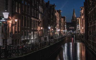 Canal amidst buildings in city at night