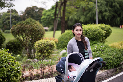 Portrait of woman standing by baby in stroller