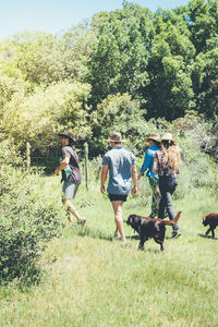 People walking on grassland against trees