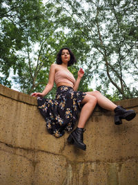 Portrait of smiling young woman sitting against trees