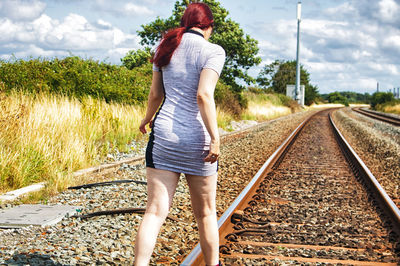 Rear view of woman standing on railroad track