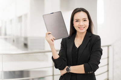 Portrait of a smiling young woman holding smart phone