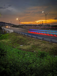 Light trails on street against sky during sunset