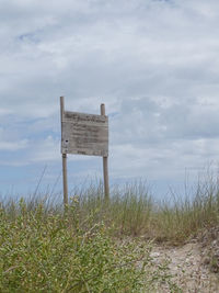 Information sign on field against sky