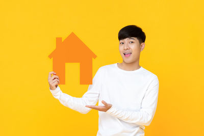 Portrait of smiling man standing against yellow background