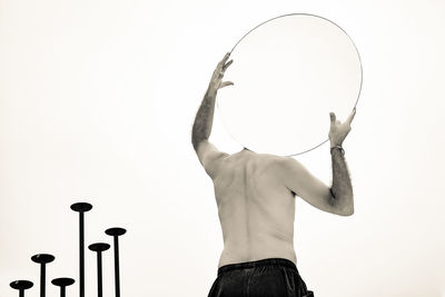 Low angle view of man holding mirror against white background