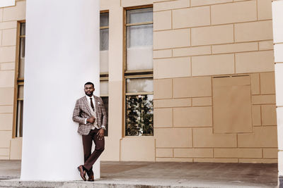 Full length of man wearing suit standing against wall