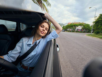 Portrait of woman sitting on car