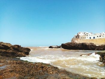 Rocks on beach against clear blue sky