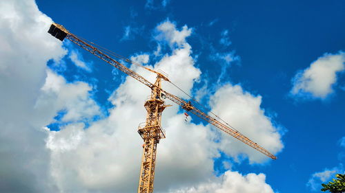 Low angle view of crane against cloudy sky