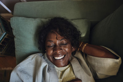 Directly above view of happy mature woman relaxing on sofa in living room at home