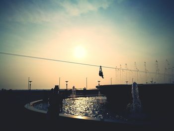 Silhouette of bridge over river during sunset