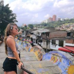 Smiling young woman in city against sky