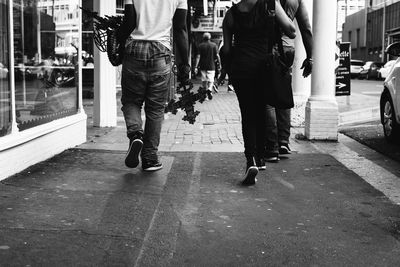 Rear view of people walking on street in city