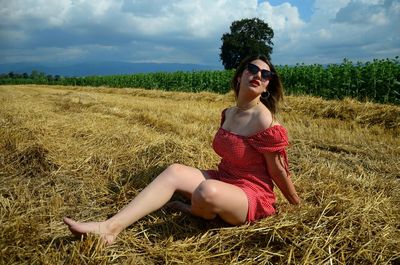 Full length of young woman standing on field against sky