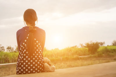 Woman standing on field against sky during sunset