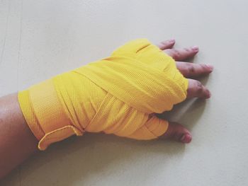 Cropped hand with yellow bandage on table