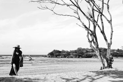 Side view of woman standing on field against sky