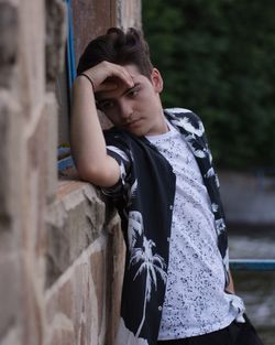 Thoughtful teenage boy leaning on stone wall