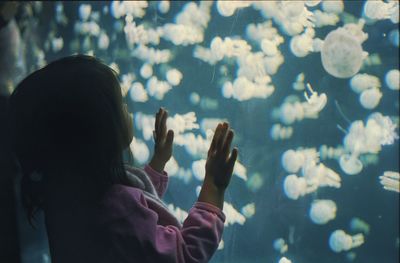 Girl looking at jellyfish swimming in aquarium