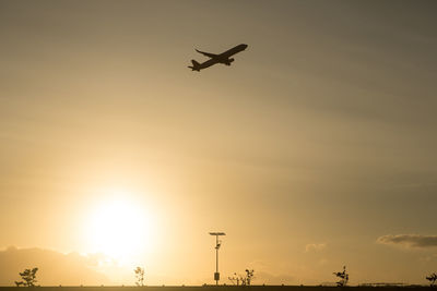 Low angle view of silhouette airplane against sky during sunset