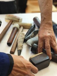 Cropped image of hands picking tools on table