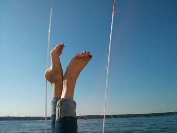 Close-up of human feet pointed upwards from a boat on a body of water