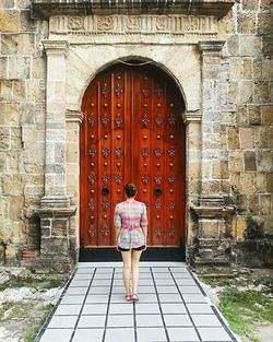 Rear view of man standing against door