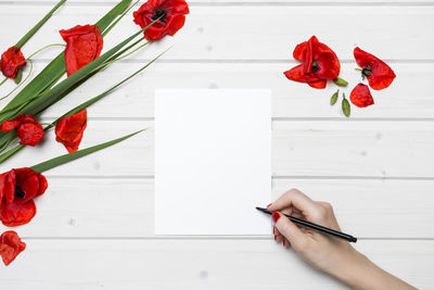 Person holding red flowers on table