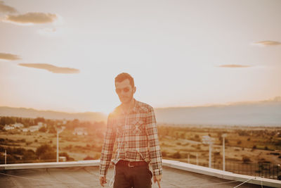 Man standing on terrace against sky during sunset