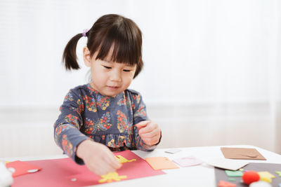 Cute girl looking away while sitting on table