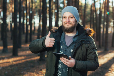 Portrait of young man using mobile phone in forest