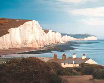 Scenic view of beach and cliffs against sky