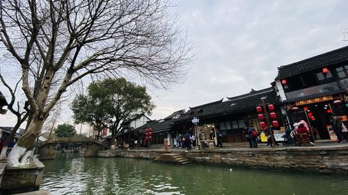 People by river amidst buildings against sky