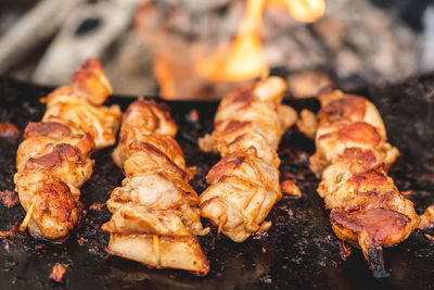 Preparing chicken meat skewers, grilled or roasted in a barbecue on an open fire and flames
