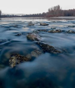 Surface level of rocks in river against sky