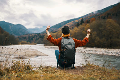 Rear view of man standing on mountain against sky