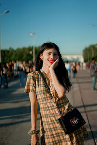 Portrait of young woman standing against sky