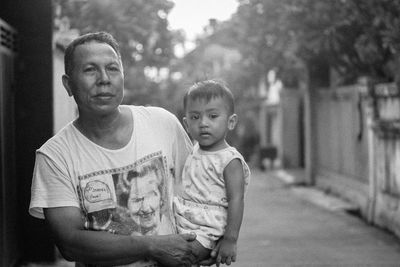 Portrait of father with granddaughter standing outdoors