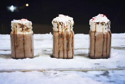 Close-up of chocolate milkshakes served on snow covered table at night