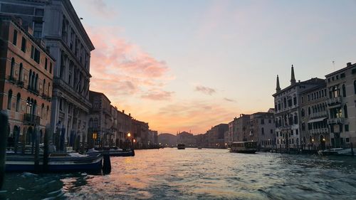 Canal passing through city at sunset