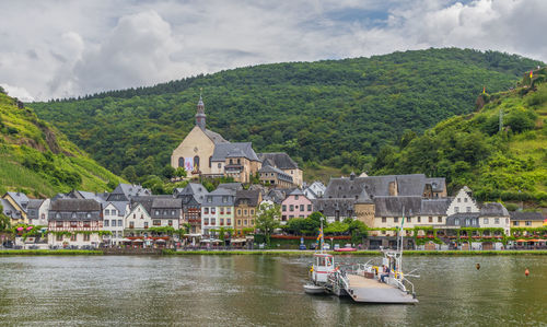 Scenic view of river by buildings against sky