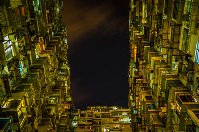 Low angle view of illuminated buildings against sky at night